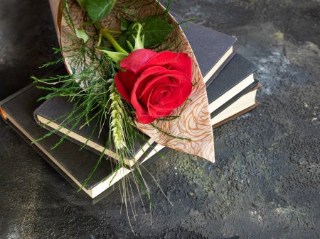 Stapelweise Bücher und rote Rose mit Ähre, traditionelles Geschenk von Sant Jordi zum Tag von Sant Jordi. Katalanische Version des Valentinstages