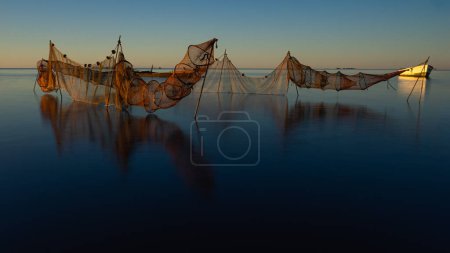 Foto de Red de pesca en las tranquilas aguas de un amanecer en el delta del Ebro, Cataluña, España. Concepto de pesca. - Imagen libre de derechos
