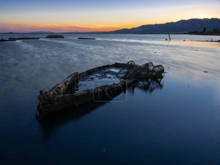 Foto de Un viejo barco abandonado y hundido en la costa con una red de pescadores. - Imagen libre de derechos