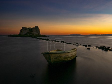 Beautiful sunset in the delta of the Ebro river next to the tower of Sant Joan and an abandoned boat. Tarragona, Spain