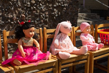 Téléchargez les photos : Grande poupée pour enfants et peluche. Une poupée et un jouet doux sont assis sur des chaises. - en image libre de droit