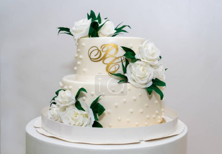 Photo for Two-tiered white wedding cake decorated with white roses. - Royalty Free Image