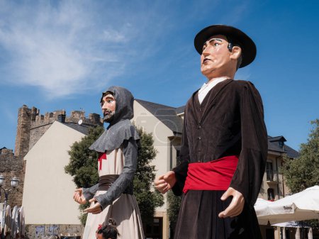 Foto de Ponferrada, León, España - 09 07 2023: Dos gigantes caminando por las calles de Ponferrada durante las festividades de Encina junto al castillo templario. Enormes muñecos vestidos como templarios y civiles - Imagen libre de derechos