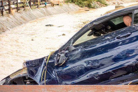 Photo for Luxury car destroyed on the banks of a river after a strong summer storm after being swept away by the force of the water - Royalty Free Image