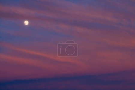 Luna Perigeo (Superluna) rodeada de nubes púrpuras al atardecer con un cielo azul oscuro, el punto más cercano de nuestro satélite al planeta Tierra