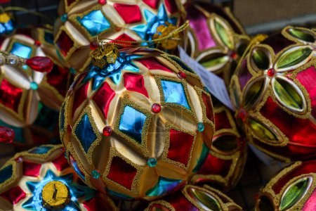 Téléchargez les photos : Boules de Noël en verre décoratif - Arlequins en dentelle en rouge, bleu et or exposés dans un stand de marché à Harrogate, Yorkshire du Nord, Angleterre, Royaume-Uni. - en image libre de droit