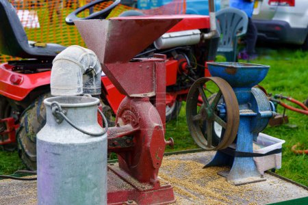 Foto de Separador de crema de hierro fundido rojo operado a mano vintage de los años 50 o 60 y un batido de leche de acero junto a una amoladora de granos, Nidderdale Show, Yorkshire del Norte, Inglaterra, Reino Unido. - Imagen libre de derechos