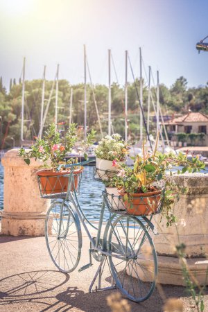 Foto de Antique blue bicycle with flowers in a basket. Bicycle on the pier against the background of yachts. - Imagen libre de derechos