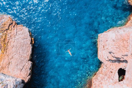 Foto de A woman swimming in the water with rocks in the background - Imagen libre de derechos
