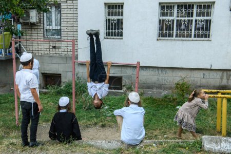 Téléchargez les photos : Les enfants, ultra-orthodoxes pèlerins juifs hassidiques, jouent dans la rue près de la tombe du rabbin Nachman à la veille de Roch Hachanah vacances, Nouvel An juif, au milieu de la Russie continue la guerre en Ukraine. Uman 16-09-2023 - en image libre de droit