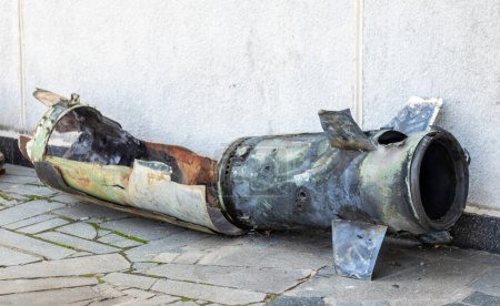 Foto de Un fragmento de metal de un cohete militar yace en el suelo después del bombardeo de una casa civil. Disparos de cohetes contra la ciudad y el horror de la guerra. Guerra de Ucrania. El proyectil está en el suelo - Imagen libre de derechos