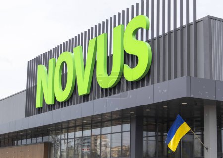 Téléchargez les photos : La chaîne de supermarchés ukrainienne Novus. Grand panneau vert du centre commercial à l'extérieur, dans la rue. Panneau contre le ciel. La construction du supermarché. Ukraine, Kiev - 01 mai 2023 - en image libre de droit
