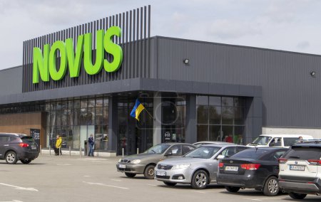 Téléchargez les photos : La chaîne de supermarchés ukrainienne Novus. Grand panneau vert du centre commercial à l'extérieur, dans la rue. Panneau contre le ciel. La construction du supermarché. Ukraine, Kiev - 01 mai 2023 - en image libre de droit