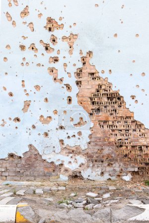 Die Mauer eines von Raketenteilen zerstörten Gebäudes in einem Kriegsgebiet. Beschädigte Mauer. Fassade eines ausgebombten Gebäudes. Bewaffneter Konflikt in der Ukraine. Schäden am Haus durch Artilleriebeschuss