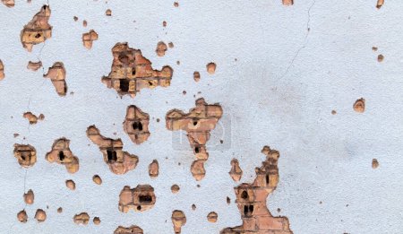 Téléchargez les photos : Le mur d'un bâtiment frappé par des fragments de fusée dans une zone de guerre. Mur bombardé. Façade d'un immeuble bombardé. Conflits armés en Ukraine. Dommages à la maison suite au bombardement de l'artillerie - en image libre de droit