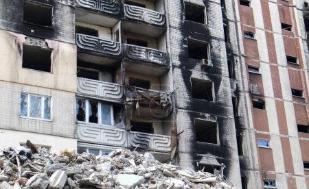 Foto de The destruction of a multi-storey building after being hit by an artillery shell. A burned-out high-rise building in a war zone. War in residential areas, broken windows and burnt apartments - Imagen libre de derechos