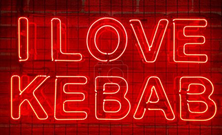 Cartel luminoso de neón en color rojo en una pared de ladrillo con la inscripción o el eslogan Me encanta el kebab. Muro de ladrillo, fondo. Luz de neón eléctrica brillante. Café-restaurante Doner Kebab