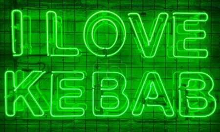 Neon shining sign in green color on a brick wall with the inscription or slogan I love kebab. Brick wall, background. Bright electric neon light. Cafe-restaurant Doner Kebab