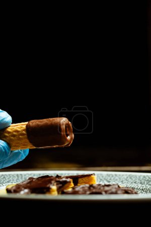 Photo for Closeup of chef holding rolled wafers with chocolate - Royalty Free Image