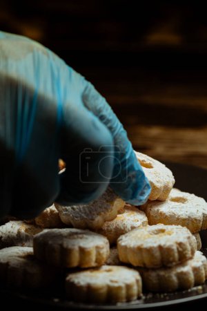 Téléchargez les photos : Gros plan de l'homme main tenant des biscuits faits maison avec de la poudre de sucre - en image libre de droit