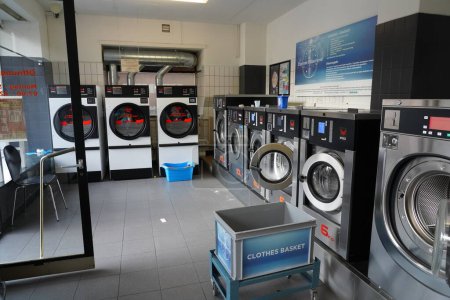 Photo for Indoor shot of public laundry for coin wash. Open wash machine and dryer and chair for waiting, 11. September 2021 at Zurich. - Royalty Free Image