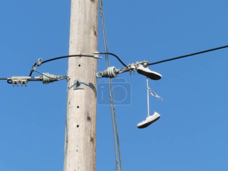 Foto de Sneakers Hanging from Power Lines. Concept: Secret Message, shoefiti or shoe tossing - Imagen libre de derechos