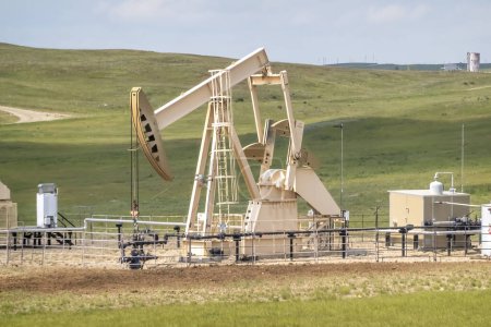 Téléchargez les photos : Bac de pompage de puits de production de pétrole brut dans une zone rurale pendant l'été. - en image libre de droit