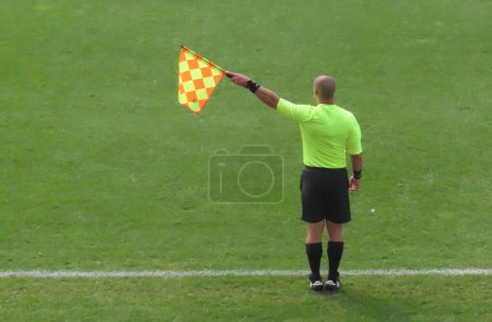 Téléchargez les photos : Un assistant arbitre tenant un drapeau extérieur lors d'un match de football. - en image libre de droit