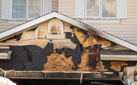 Una vista de cerca de un techo de garaje del barrio, que lleva las cicatrices de los recientes daños accidentales por incendio, expertamente extinguido por los bomberos en medio de un tranquilo otoño.