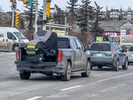 Téléchargez les photos : Calgary, Alberta, Canada. 15 février 2024. Une camionnette Sierra 1500 transportant une motoneige couverte pendant l'hiver. - en image libre de droit