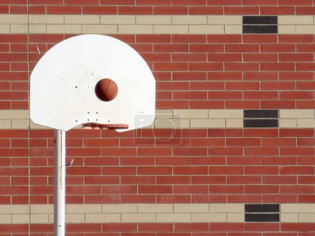 Ein Basketball, der rechtzeitig aufgehängt wird, kurz vor seiner Flugbahn zum festen Rand des Punktekorbs.