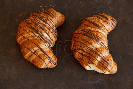 Croissant con mantequilla dos piezas en un tablero negro. Foto de alta calidad