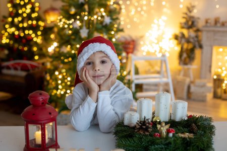 Photo for Cute preschool child, blond boy, making advent wreat at home in decorated Christmas room at home - Royalty Free Image