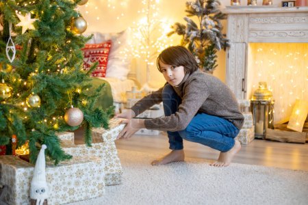 Téléchargez les photos : Enfant mignon, garçon, jouer dans la chambre décorée pour Noël, décorer Noël tre - en image libre de droit