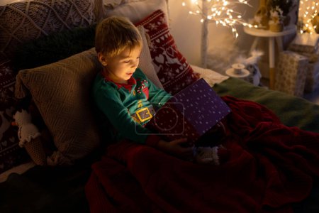 Foto de Lindo niño preescolar, niño rubio con perro mascota, regalos de apertura en casa, decorado habitación de Navidad en casa - Imagen libre de derechos
