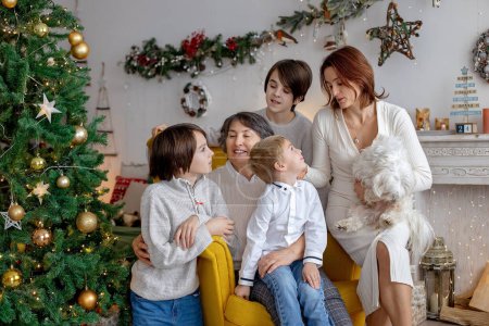 Foto de Cuadro familiar de Navidad en casa acogedora con luces y decoración, abuela, madre e hijos - Imagen libre de derechos