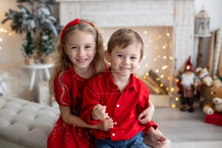 Téléchargez les photos : Happy cute children, siblings on Christmas, enjoying holiday, opening presents and eating cookies - en image libre de droit