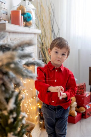 Téléchargez les photos : Happy cute child on Christmas, enjoying holiday, opening presents and eating cookies - en image libre de droit
