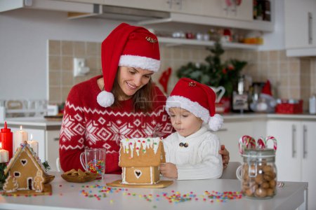 Photo for Blond toddler child and mom, cute boy and mother, decorating Christmas ginger bread house at home - Royalty Free Image