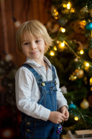 Téléchargez les photos : Enfant en bas âge, mignon garçon blond, décoration arbre de Noël, lumières de Noël autour de lui - en image libre de droit