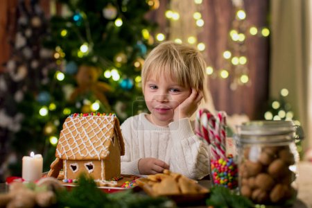 Téléchargez les photos : Enfant blond tout-petit, garçon mignon, faisant maison de pain d'épice de Noël à la maison - en image libre de droit