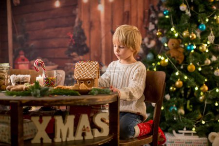 Photo for Blond toddler child, cute boy, making Christmas ginger bread house at home - Royalty Free Image
