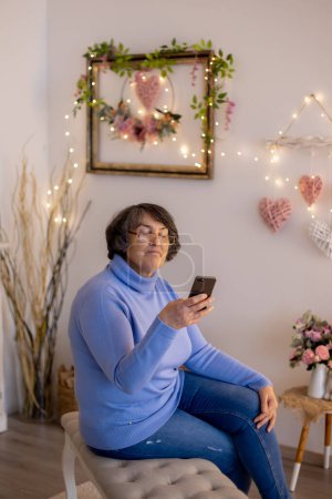 Téléchargez les photos : Elderly woman, posing at home, sitting on sofa or bed - en image libre de droit