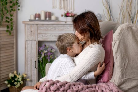 Téléchargez les photos : Cute blonde toddler child, boy, cuddling  in mother, sitting on an armchair, smiling and hugging, Valentines day - en image libre de droit