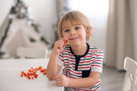 Foto de Lindo niño pequeño, niño pequeño, comer alfa omega 3 suplemento infantil píldoras vitamínicas en casa para una mejor imunidad - Imagen libre de derechos