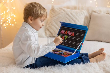 Foto de Cute little preschool child, playing with alphabet game, learning letters and words at home, preparing for school - Imagen libre de derechos