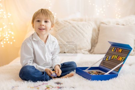 Photo for Cute little preschool child, playing with alphabet game, learning letters and words at home, preparing for school - Royalty Free Image