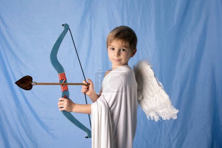 Foto de Little cupid toddle boy, holding bow and arrow, beautiful blond cherub, love - Imagen libre de derechos