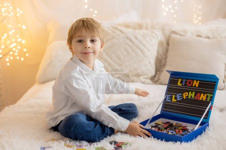 Téléchargez les photos : Cute little preschool child, playing with alphabet game, learning letters and words at home, preparing for school - en image libre de droit