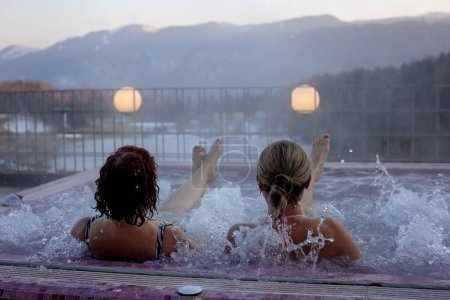 Téléchargez les photos : Les gens, profitant d'un bain tourbillon et saunta après la journée de ski, se détendre dans un beau bain tourbillon nain en plein air, vue splendide sur un coucher de soleil - en image libre de droit